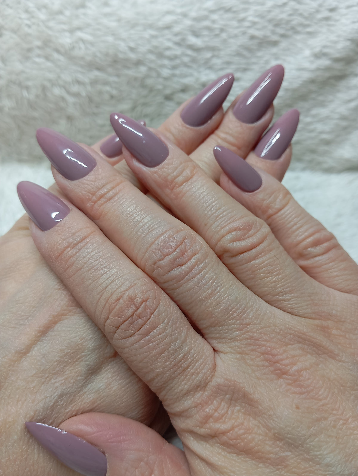 Press-on nails mauve taupe brillants en forme amande portés sur les deux mains