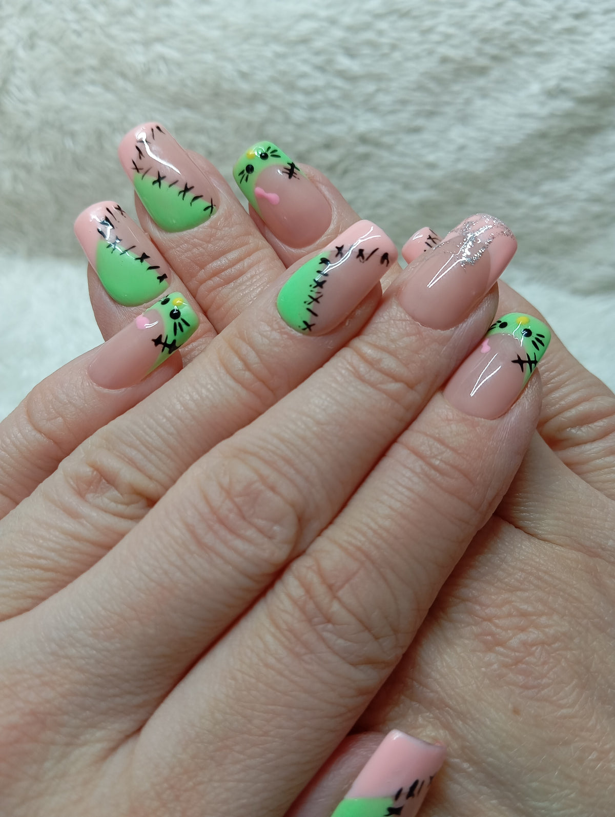 Press-on nails rose et vert néon avec coutures noires et petits visages de monstre